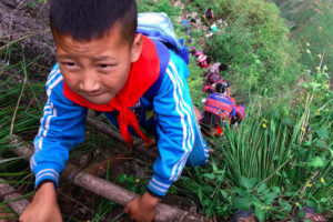 In this May 14, 2016 photo, children wearing their school backpacks climb a cliff on their way home from school in Zhaojue county, southwest China's Sichuan province. A village in China's mountainous west where school children must climb an 800-meter (2,625-foot)-high bamboo ladder secured to a sheer cliff face may get a set of steel stairs to improve it's safety. (Chinatopix via AP) CHINA OUT